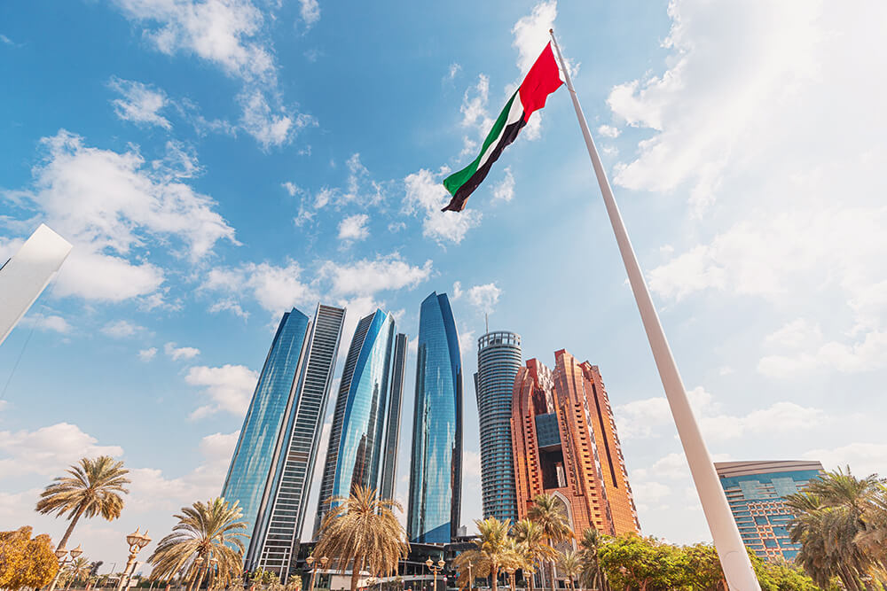 low-angle-view-uae-flag-waving-with-modern-skyscrapers-background-abu-dhabi